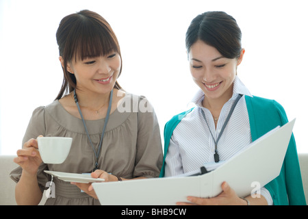 Japan, Osaka Prefecture, Businesswoman holding coffee cup, discussing Stock Photo