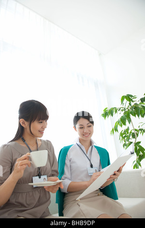 Japan, Osaka Prefecture, Businesswoman holding coffee cup, discussing Stock Photo