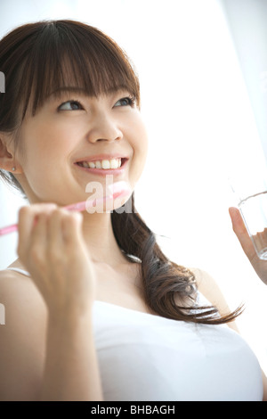Japan, Osaka Prefecture, Woman holding brushing, smiling, close-up Stock Photo