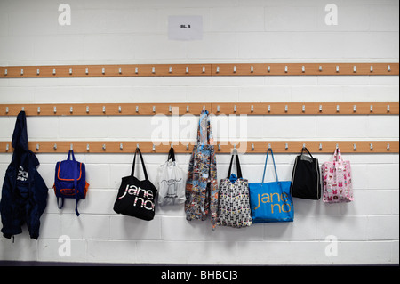 Bags hanging up on coat hooks in a secondary school cloakroom, UK Stock Photo