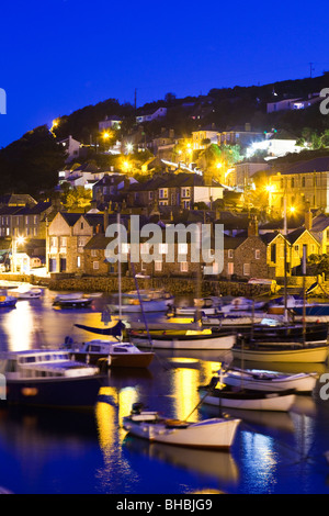 Night falling on boats swaying on the tide in the harbour in the old fishing village of Mousehole, Cornwall Stock Photo