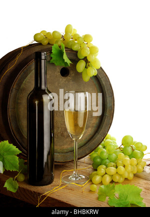 Still life with white wine bottle, glass, old wine barrel, grapes and fresh grapevine leaves, isolated on white background Stock Photo