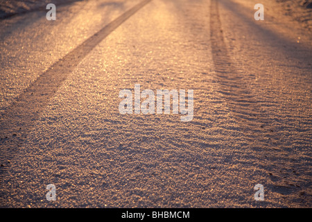 Car tire tracks on first snow at sunset , Finland Stock Photo
