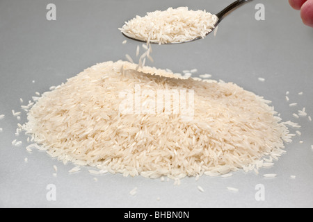 Tablespoonful of white uncooked Basmati rice being lifted from a pile Stock Photo