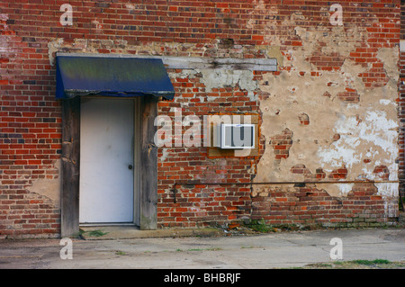 Old brick wall with door, awning and window air conditioner Stock Photo