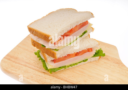 turkey and cheese sandwiche on white bread with lettuce and tomatoe stacked on a cutting board on white background. Stock Photo