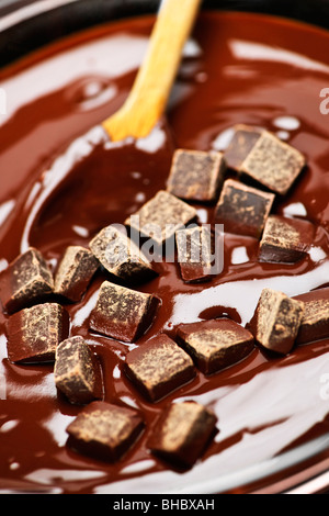 Wooden spoon stirring melting rich chocolate chunks Stock Photo