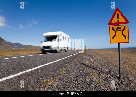 Motion blurred photograph motor home or camper van driving on an open road with danger sign Stock Photo