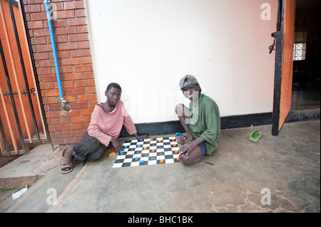 Two homeless boys playing draughts in centre, Kampala Uganda Stock Photo