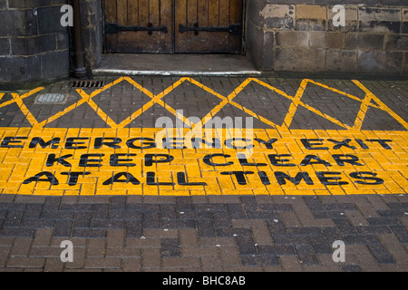 Sign painted on pavement outside an old stone public building EMERGENCY EXIT KEEP CLEAR AT ALL TIMES Stock Photo