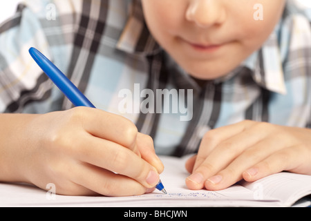 Close up of a schoolboy doing homework, half of face visible and in blur Stock Photo