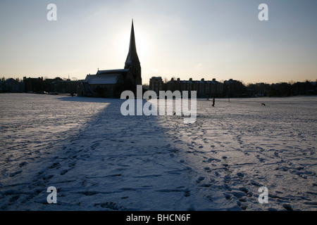 All Saints church casts it shadow over a snowy Blackheath Common, Blackheath, London, UK Stock Photo