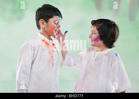 Girl putting colour on a boy Stock Photo