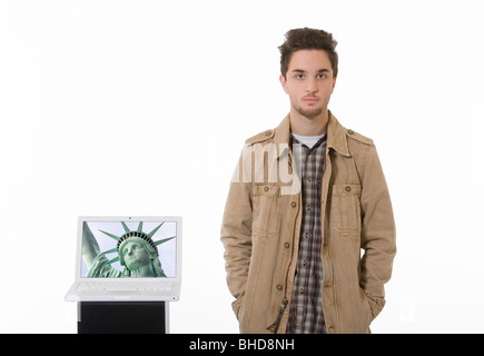 Young man stands next to his laptop computer. Stock Photo