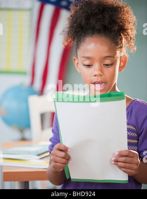 Mixed race girl reading report at school Stock Photo