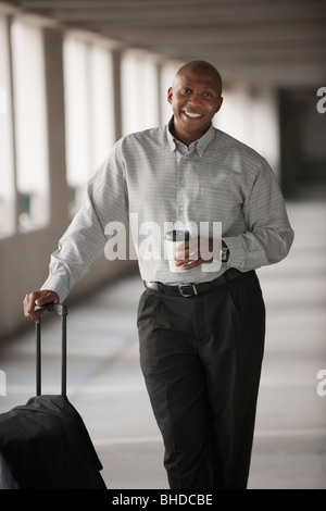 African businessman standing in parking garage with luggage Stock Photo