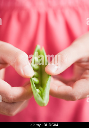 Mixed race girl opening pea pod Stock Photo