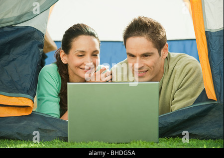 Hispanic couple using laptop in tent Stock Photo
