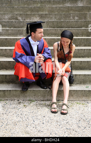Graduate sitting with his girlfriend on the stairs Stock Photo