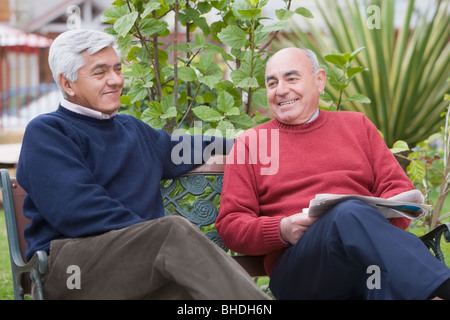 Senior Hispanic friends sitting on park bench Stock Photo