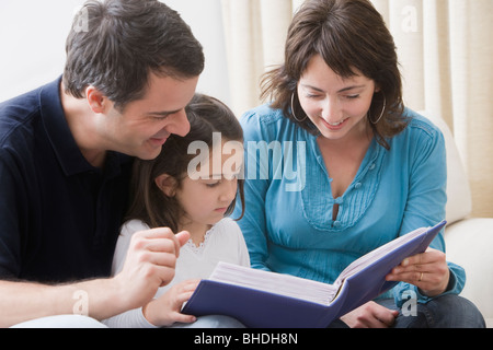 Hispanic parents reading book to daughter Stock Photo
