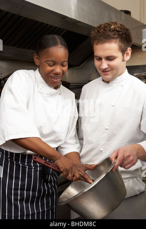 Chef Instructing Trainee In Restaurant Kitchen Stock Photo