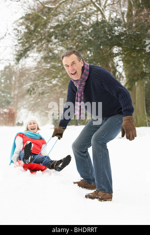 Senior Couple Sledging Through Snowy Woodland Stock Photo