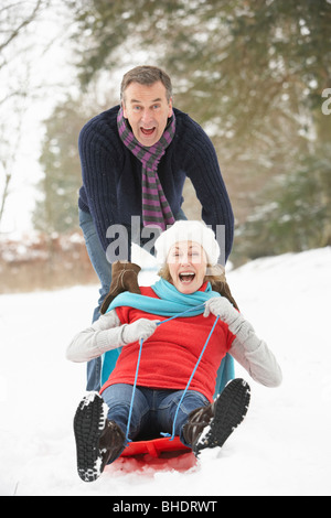 Senior Couple Sledging Through Snowy Woodland Stock Photo