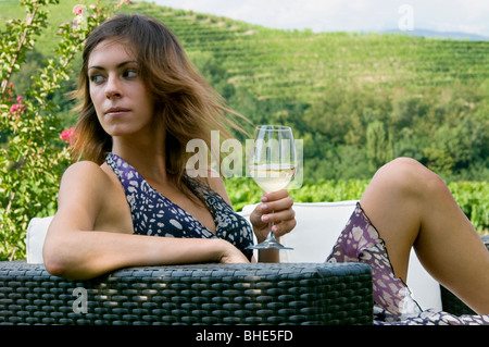 Young woman sitting on couch in vineyard with white wine Stock Photo