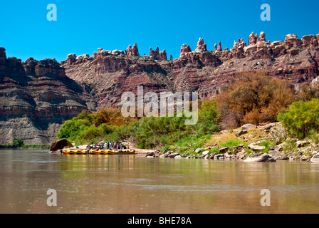 USA, Utah, Canyonlands NP. OARS rafting group on Colorado River below Maze District monolithes. Stock Photo