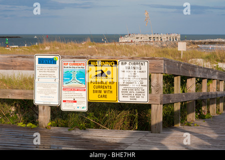 Signs warn beach visitors of water quality advisories and rip currents in the Atlantic Ocean Stock Photo