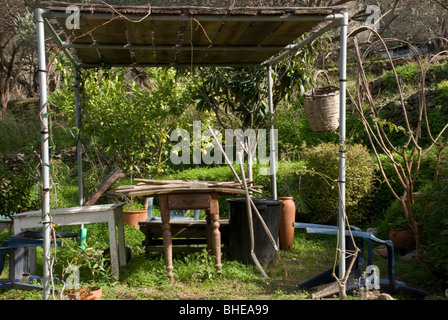 an arbor in a garden with tools and tables under it Stock Photo