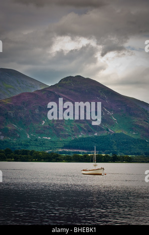 View of single moored sailing boat on Bassenthwaite Lake, Cumbria, with Ullock Pike and Skiddaw in background. Stock Photo