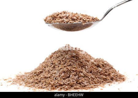 Pile of high fibre wheat bran flakes lifted on a dessert spoon Stock Photo