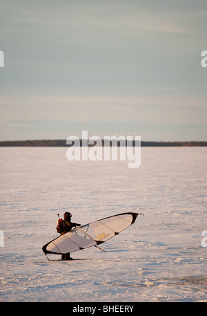 A man skiing on sea ice at Wintertime using a kitewing  at Baltic Sea , Gulf of Bothnia , Finland Stock Photo