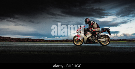 Side view of motorbike and rider riding along road on the North Yorkshire Moors, UK Stock Photo