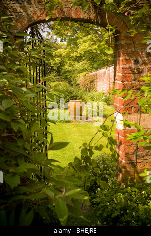 Partially open wrought iron gate leading into a secret garden. UK Stock Photo