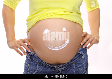 Pregnant woman shows a smiley on her belly Stock Photo