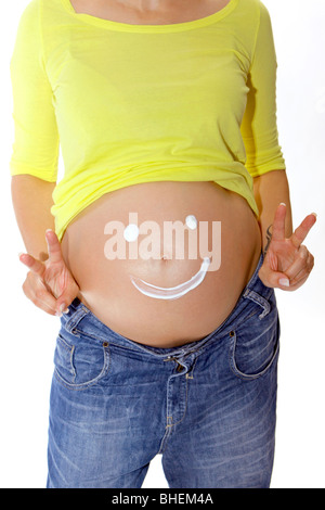 Pregnant woman shows a smiley on her belly, victory ok sign Stock Photo