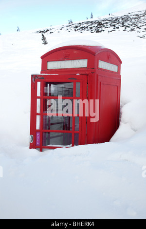 Deep snow almost buries a traditional red telephone box on the mountains in Aviemore, Cairgorms, Scotland. Stock Photo