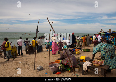 local people and colorfully painted fishing boats in Tanji fishing village Gambia Africa Stock Photo