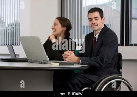 Handicapped businessman working on a laptop with a businesswoman Stock Photo