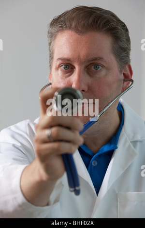 Portrait of a male doctor holding a stethoscope against a white ...