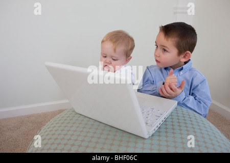 Boy signing the word 'Help' in American Sign Language with his brother in front of a laptop Stock Photo