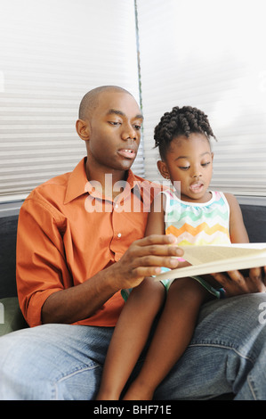 Black father reading book to daughter Stock Photo