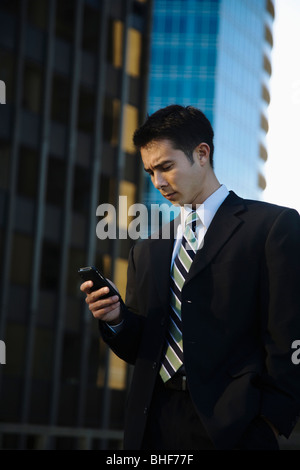 Mixed race businessman text messaging on cell phone Stock Photo