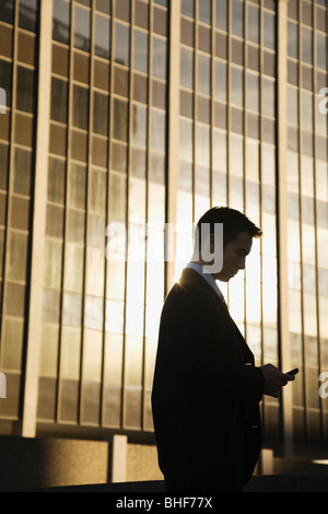 Mixed race businessman text messaging on cell phone Stock Photo