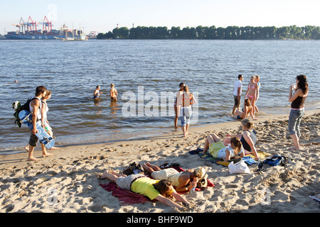 Sunbathing at sandy beach of river Elbe, light ship Elbe 3 in ...