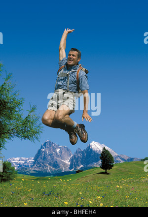 A man wearing leather trousers cutting a caper on an alpine meadow, Alpe di Siusi, South Tyrol, Italy, Europe Stock Photo