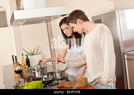 Young couple cooking in kitchen together drinking red wine Stock Photo